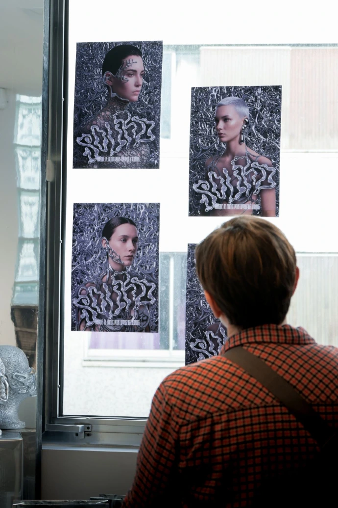 Visiteur observant des affiches de design graphique exposées en vitrine