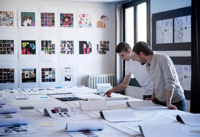 Étudiants examinant des planches d'illustration graphique en atelier au campus ESDAC Aix-en-Provence