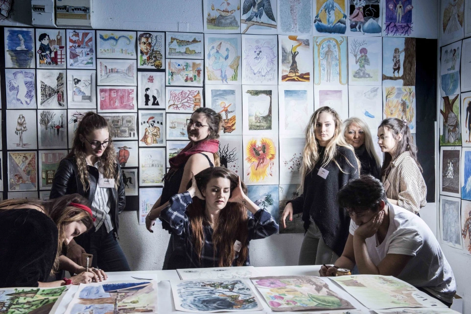 Étudiants posant devant un mur d'illustrations aquarelle au campus ESDAC Clermont-Ferrand