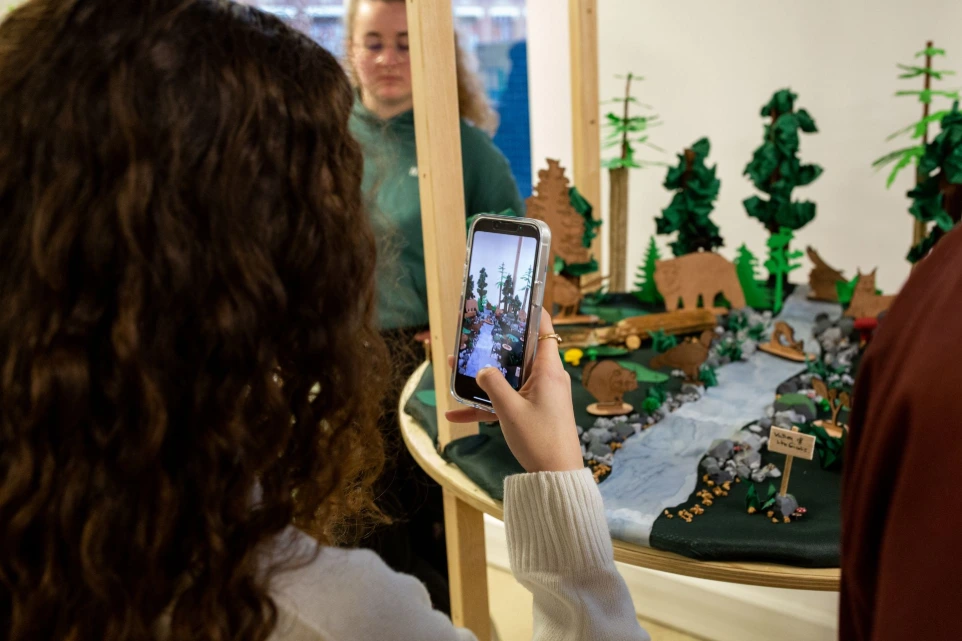 Étudiante photographiant une maquette de décor forestier réalisée au campus ESDAC Lille