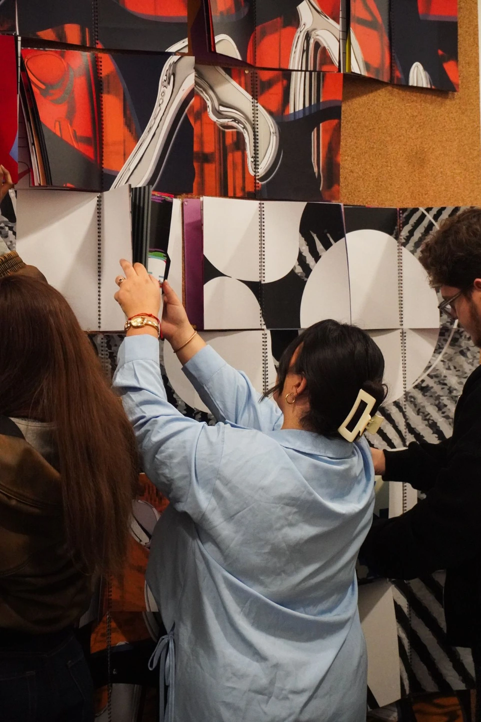 Étudiants accrochant leurs travaux graphiques sur un mur d'exposition au campus ESDAC Marseille
