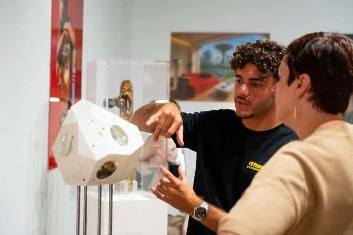 Étudiant présentant un objet design à une visiteuse lors d'une exposition