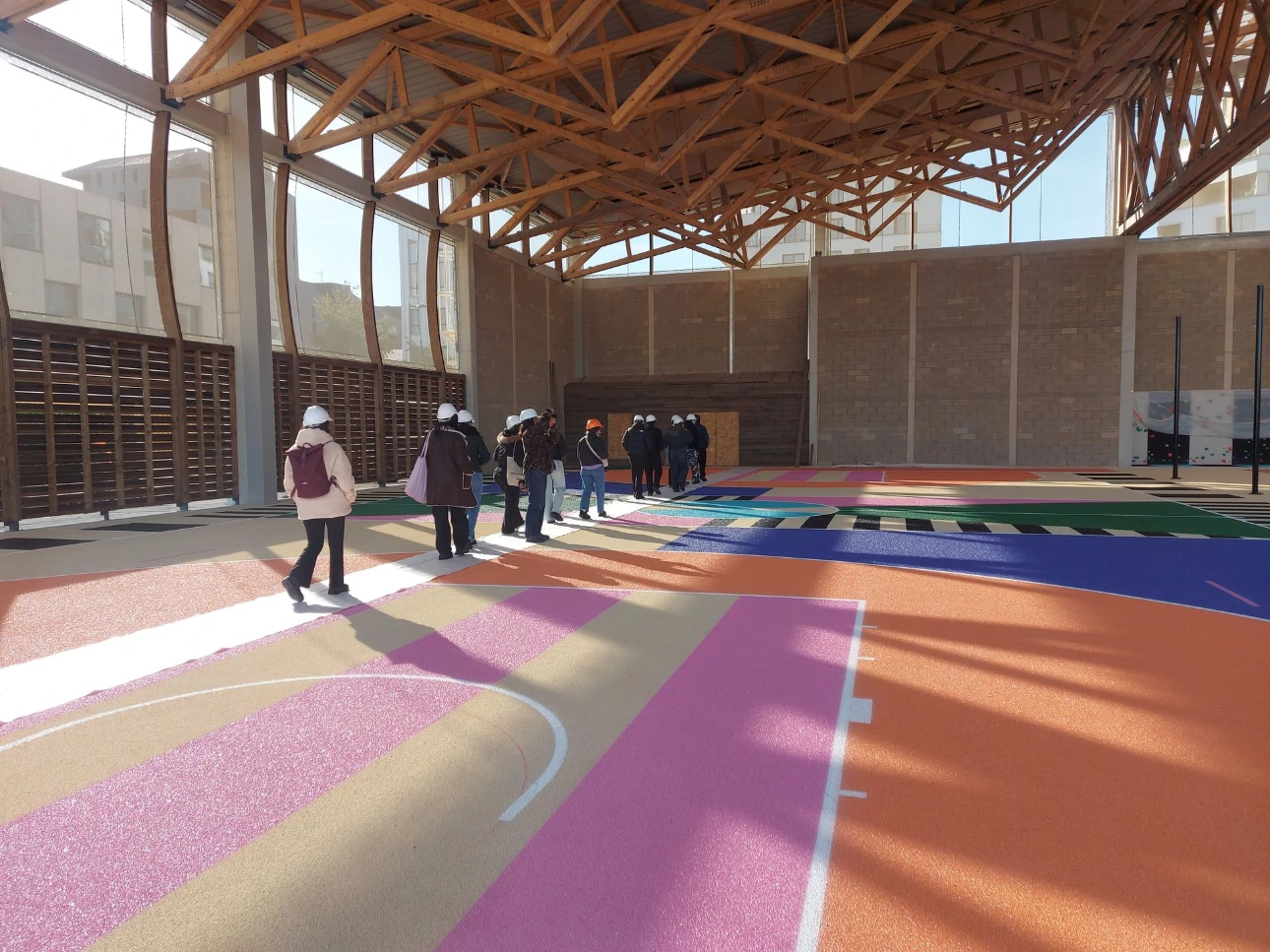 Visite d'un équipement sportif en construction par un groupe muni de casques de chantier